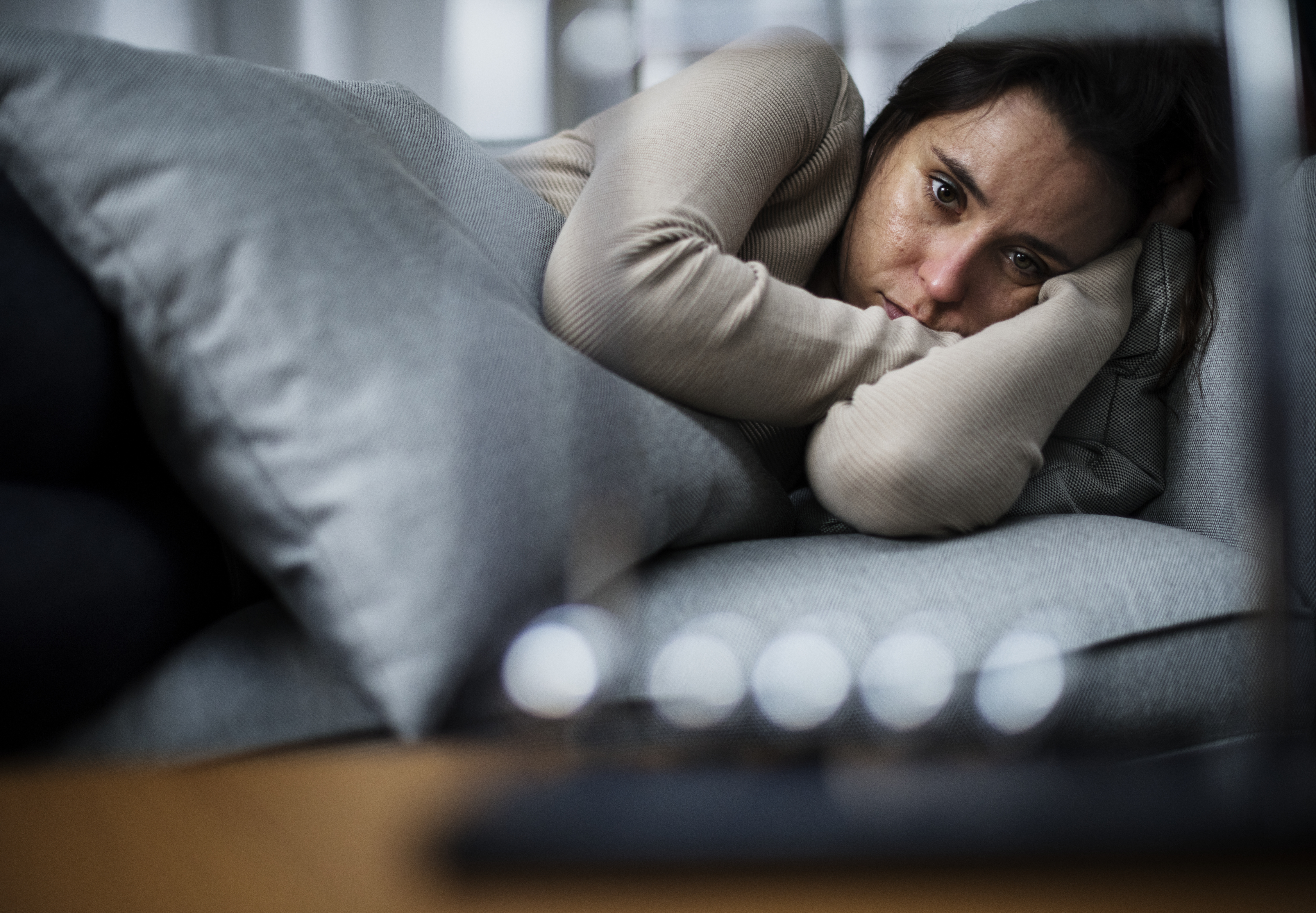 woman lying on couch looking distraught