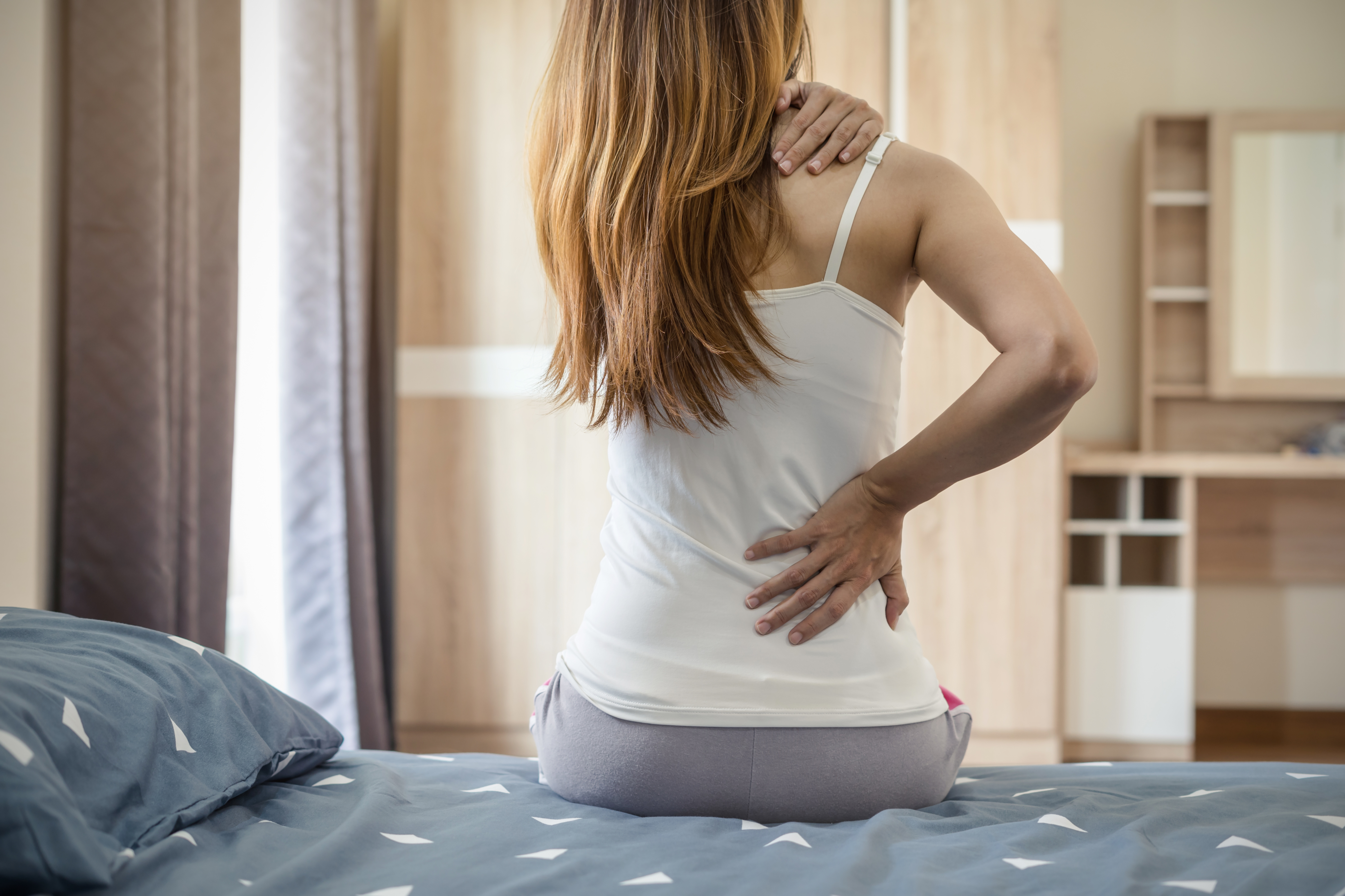 woman holding her back and shoulder in pain