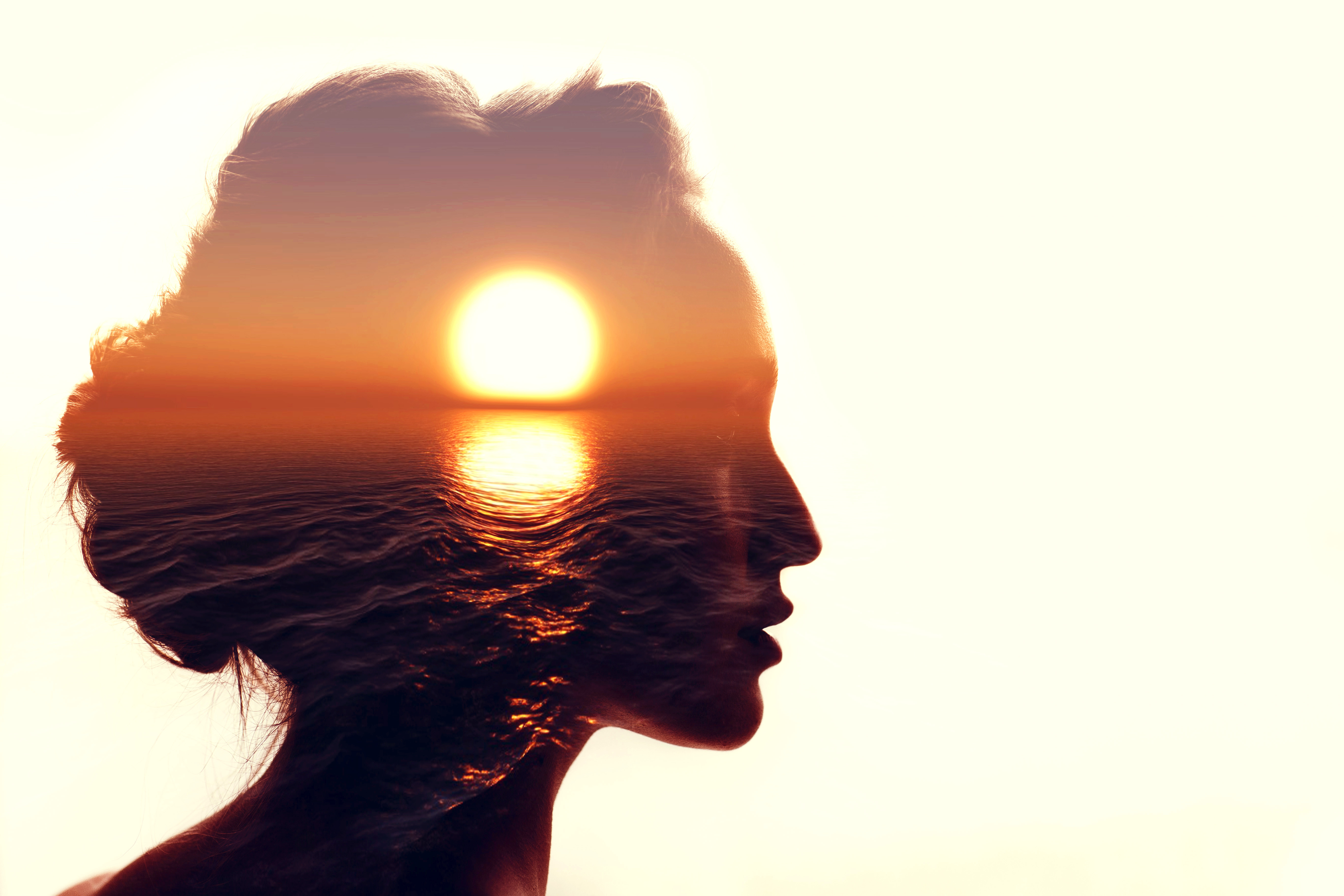 sunset on ocean horizon overlaid within profile of woman