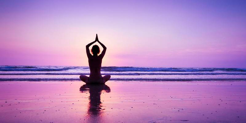 person on beach at dusk in yoga pose